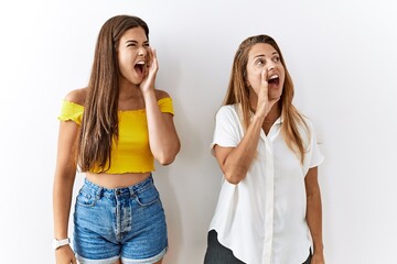 Poster - Mother and daughter together standing together over isolated background shouting and screaming loud to side with hand on mouth. communication concept.