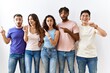 © Krakenimages.com - Group of young people standing together over isolated background surprised pointing with finger to the side, open mouth amazed expression.