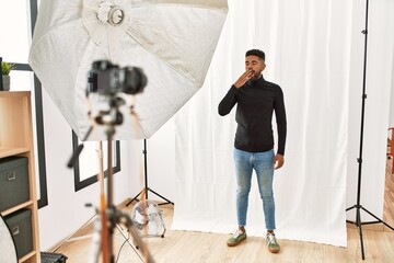 Wall Mural - Young hispanic man with beard posing as model at photography studio bored yawning tired covering mouth with hand. restless and sleepiness.