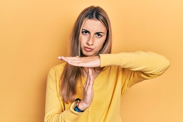 Poster - Beautiful hispanic woman wearing casual yellow sweater doing time out gesture with hands, frustrated and serious face