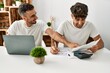 © Krakenimages.com - Two hispanic men couple smiling confident using laptop working at home
