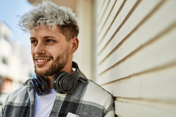 Wall Mural - Young hispanic man smiling happy using headphones at the city.