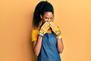 Sticker - Middle age african american woman wearing professional apron laughing and embarrassed giggle covering mouth with hands, gossip and scandal concept