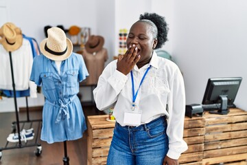 Canvas Print - Young african woman working as manager at retail boutique bored yawning tired covering mouth with hand. restless and sleepiness.