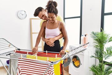 Canvas Print - Man and woman couple hugging each other hanging clothes on clothesline at laundry room