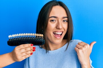 Poster - Young hispanic girl comparing teeth whitening pointing thumb up to the side smiling happy with open mouth