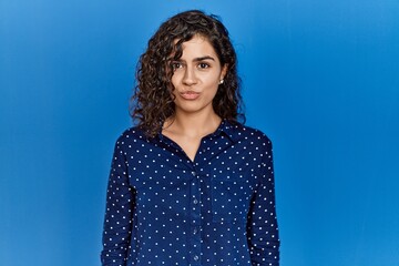 Poster - Young brunette woman with curly hair wearing casual clothes over blue background depressed and worry for distress, crying angry and afraid. sad expression.