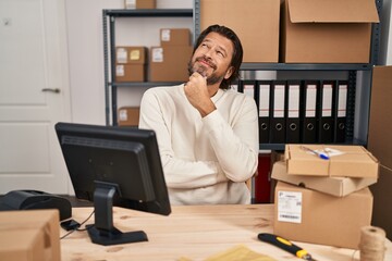 Poster - Handsome middle age man working at small business ecommerce looking confident at the camera smiling with crossed arms and hand raised on chin. thinking positive.