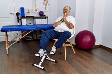 Sticker - Senior caucasian man at physiotherapy clinic using pedal exerciser praying with hands together asking for forgiveness smiling confident.