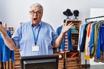 Sticker - Senior man with grey hair working as manager at retail boutique celebrating crazy and amazed for success with arms raised and open eyes screaming excited. winner concept