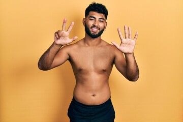 Canvas Print - Arab man with beard wearing swimwear shirtless showing and pointing up with fingers number eight while smiling confident and happy.