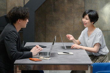 Woman and man working in a fashionable office talking to each other.