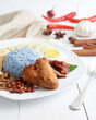 Nasi Lemak-Malaysian cuisine on white background. A fragrant rice dish cooked in coconut milk and pandan leaf commonly found in Malaysia. Served with sambal, anchovies, peanut and cucumber.