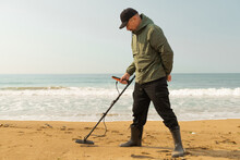 A Man With A Metal Detector And A Shovel On The Seashore. A Treasure Hunter With A Metal Detector. A Man Is Looking For A Treasure.