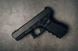 © Tanawit - black 9mm pistol on an old concrete floor. top view.