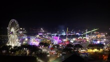 Aerial Forward Tilt Down Shot Of People Having Fun On Illuminated Rides In Fair At Night - Costa Mesa, California