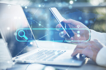 Poster - Close up of businessman hand using laptop and cellphone with creative search bar and digital blue map icons on blurry background. Address and Url concept. Double exposure.