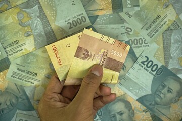 5000 IDR, Indonesian rupiah money concept, was held by businessman on money background