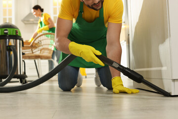 Wall Mural - Professional janitor in uniform vacuuming floor indoors, closeup