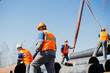 © SerPak - Group of slingers in construction helmets and vests on street unload metal pipes. Real scene. Workflow