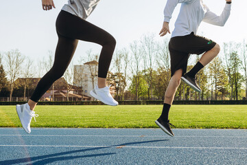 Two young men running in the stadium. Legs of runners on the sports track