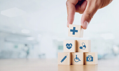 close up man hand arranging wood block with healthcare medical icon on hospital background. health c