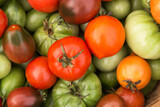 Fototapeta Kuchnia - Colorful green orange red tomatoes close-up, top view background texture