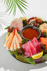 Canvas Print - Sashimi set from raw seafood: salmon, tuna, eel, perch, shrimps, sea scallop. Traditional japanesse dish - sashimi on white background. Fresh delicacy on ice with lemon, ginger and sauce.