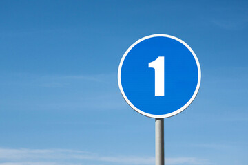 '1 (one)' sign in blue round frame. Clear sky is on background