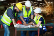© atitaph - Male and female engineers chat with factory workers as they use machine drawings, planning for industrial maintenance