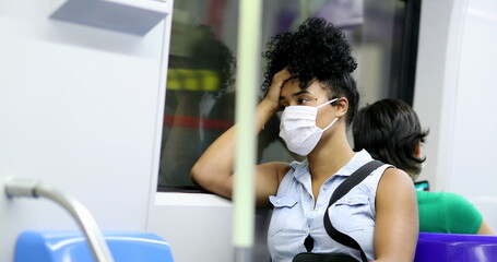 Wall Mural - African American woman riding subway checking cellphone during pandemic