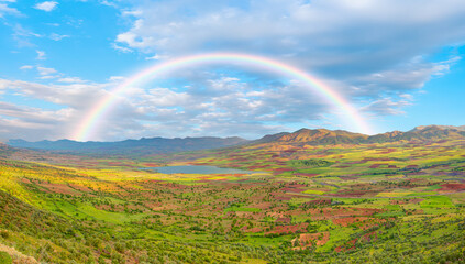  Beautiful blue lake and valley landscape with a view of the mountains and a green valley and a rainbow in the clouds