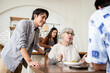 © krumanop - Happy Asian big family cooking together and preparing delicious food in kitchen. Talking and smiling while making organic salad in kitchen on the table