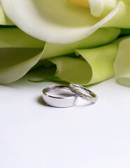 Stylish wedding rings made of white gold on a background of a bouquet of calla lilies. High quality photo