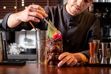 Crop Man Decorating Tiki Cocktail At Counter In Bar
