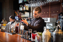 Focused Barkeepers Working At Counter In Bar