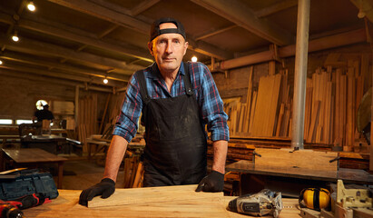 Wall Mural - Portrait of Senior Professional carpenter in uniform working in the carpentry workshop