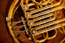 Golden Wind Instrument. French Horn On A Wooden Background. Golden French Horn With Wooden Background. Glossy Baritone Horn Musical Instrument On A Wooden Floor With Copy Space On The Right Side. 