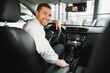 © Serhii - Taxi driver smiling while turning over to the backseat looking talking with clients. Successful businessman husband looking at the backseat at dealer shop before buying a car