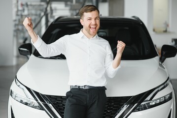 Wall Mural - Young handsome man at show room standing near car