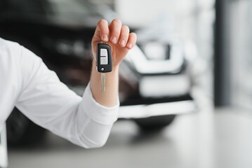 Close up of the car owner's hand holding the delivery key to buyers. Concept of selling cars and giving keys to new owners