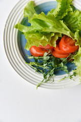 Wall Mural - Salad on a white plate tomatoes greens and peas. White background.