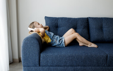Wall Mural - cute little girl at home with headphones