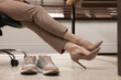 © New Africa - Comfortable sneakers on floor near woman wearing stylish high heeled shoes in office, closeup