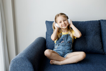 Wall Mural - cute little girl at home with headphones