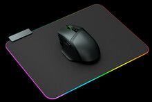 Modern gaming computer mouse on professional pad on black background