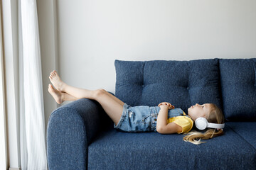 Wall Mural - cute little girl at home with headphones