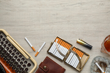 Open case with tobacco filter cigarettes, lighter, glass ashtray and wallet near vintage typewriter on wooden table, flat lay. Space for text