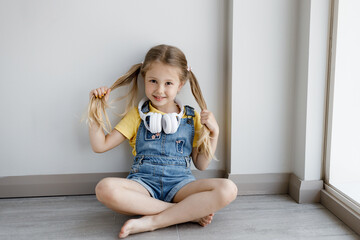 Wall Mural - cute little girl at home with headphones