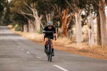 Wall Mural - Professional cyclist in sportswear practicing on a long countryside road